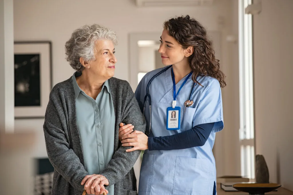 A caregiver supporting an older woman at home